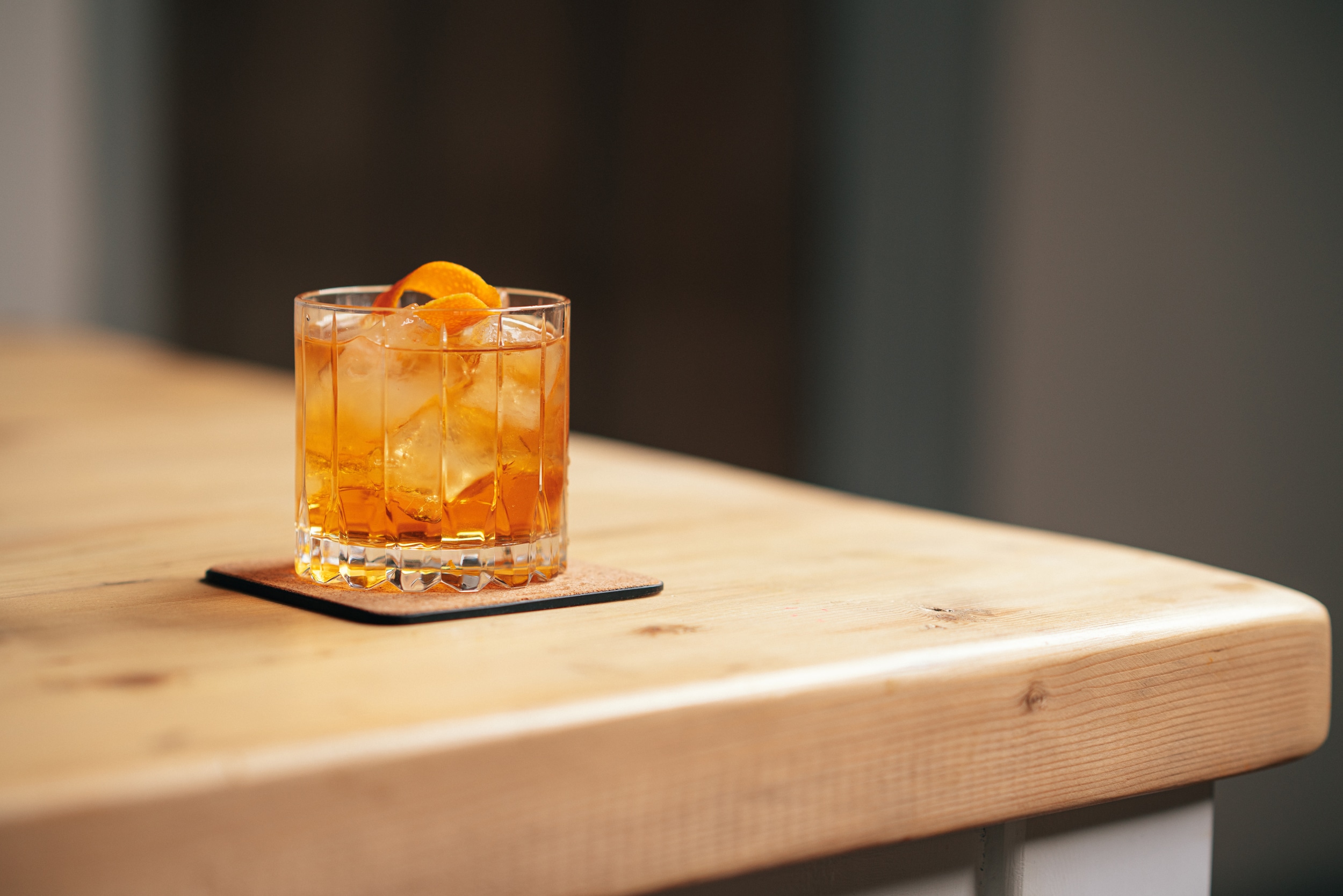 Old Fashioned Cocktail in a rocks glass with orange slice garnish on a wooden table