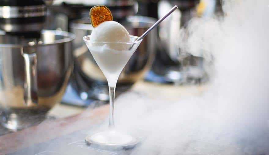 A frozen cocktail at Brozen Bar Bristol looking like a ball of white ice cream in a martini glass with a metal straw