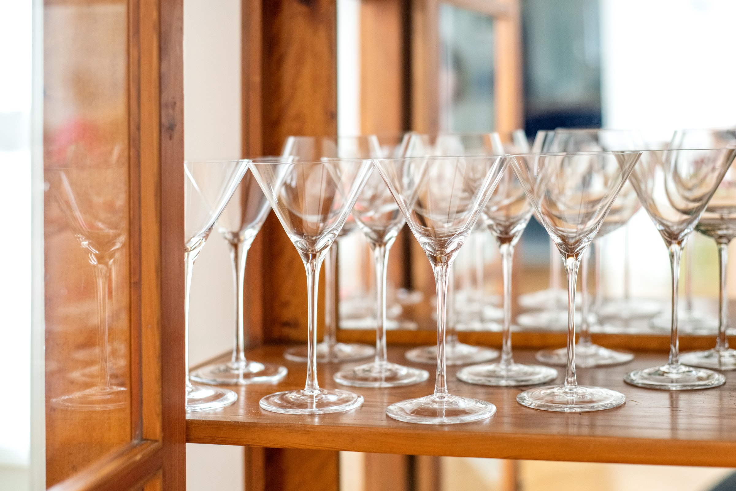 Rows of martini glasses in a wooden cabinet