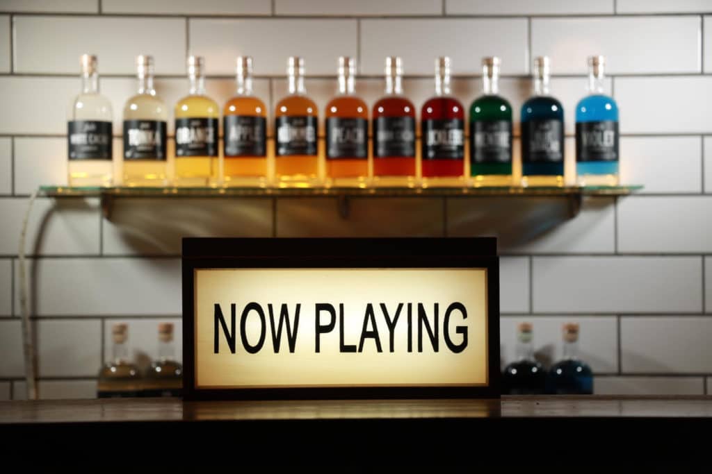 A selection of bottles next to a sign saying "now playing" at Lucky Liquor Co Edinburgh