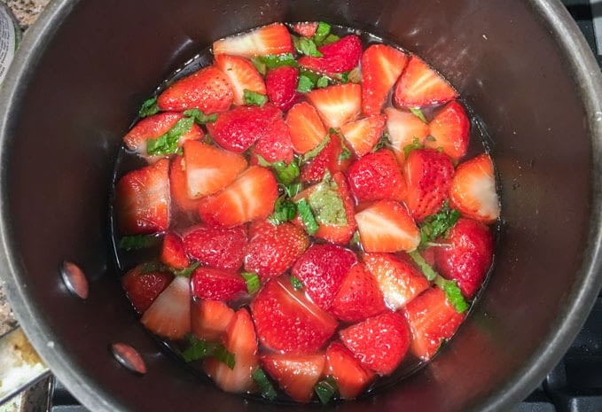 Strawberry and mint pickling in vinegar as part of the process of how to make cocktail shrubs