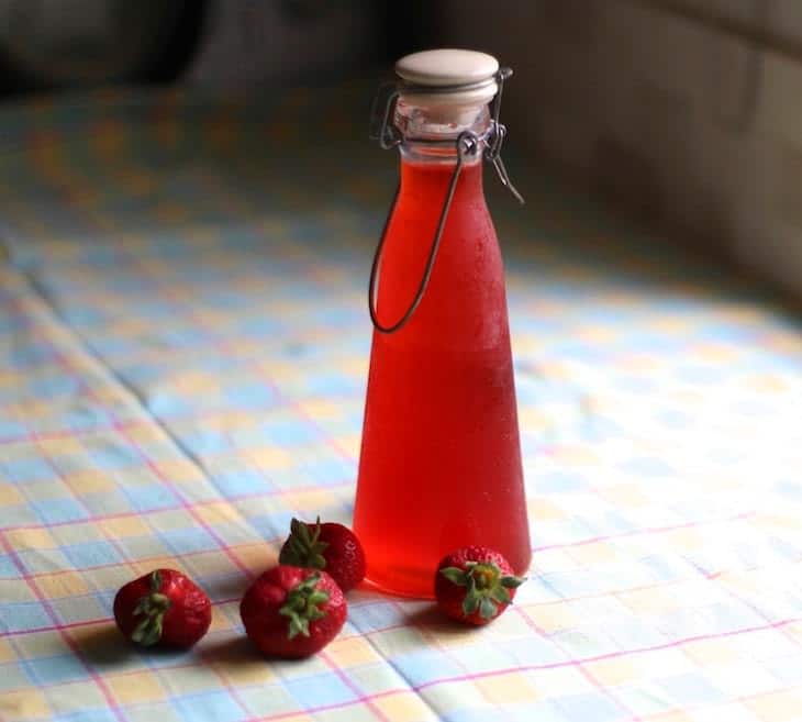 A bottle of red cocktail shrubs made with strawberries