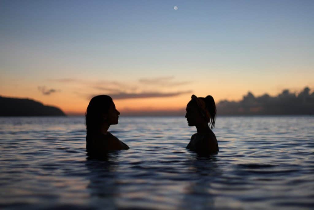 Silhouettes of two women swimming in the sea
