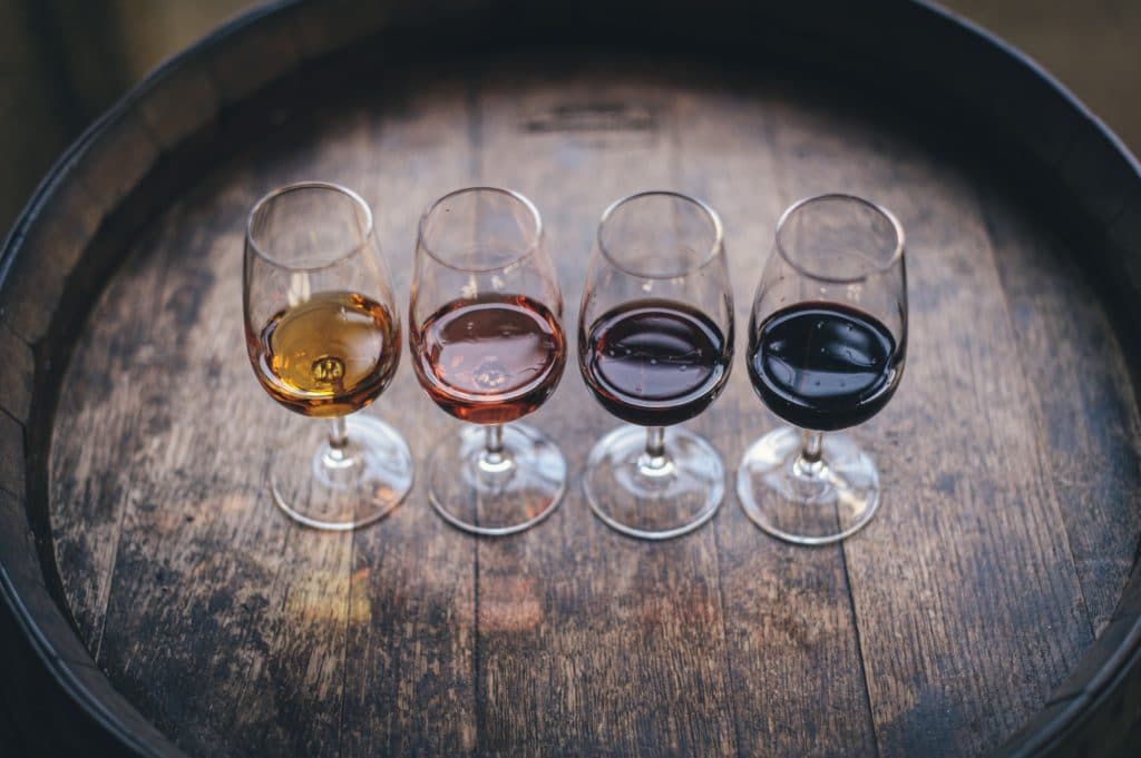 A selection of wine on a barrel with glasses of red, rose and white wine