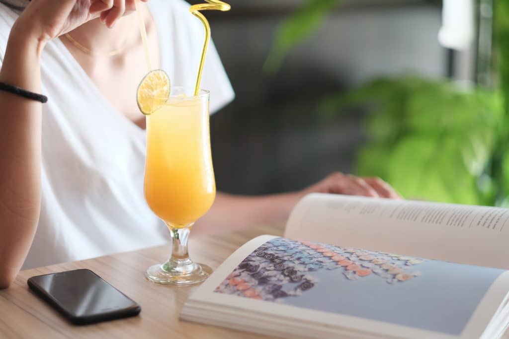 A woman reads a magazine whilst sipping from a Mother's Day cocktail recipe