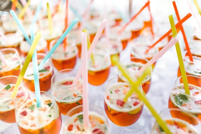 Rows of wine glasses with bright coloured straws, containing the Pimm's recipe