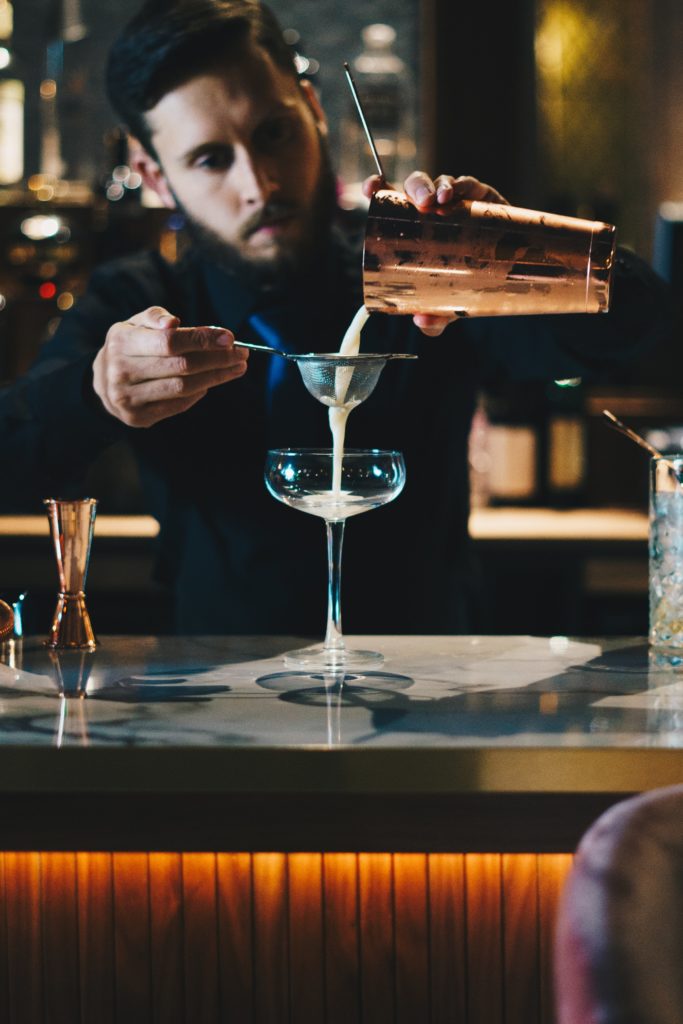 A bartender straining cocktail recipes with vodka into a coup glass.