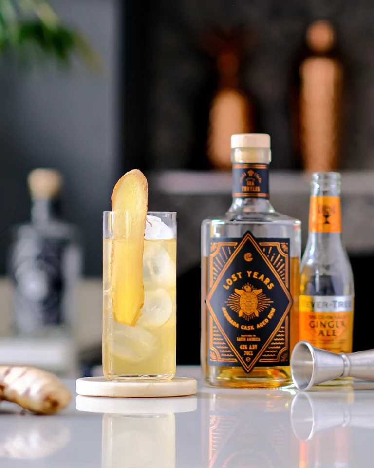 The Spiced Orange Ginger Highball, one of Lost Years Aged Rum cocktail recipes next to a bottle of Arribada Rum